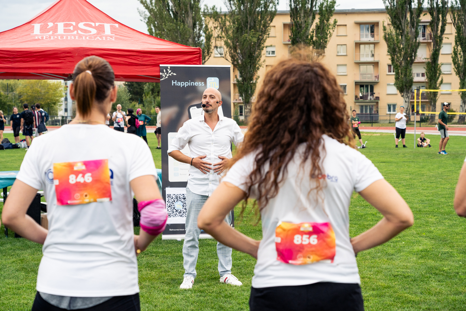 Animateur guidant un atelier de respiration en plein air devant des participants lors d’un événement sportif et bien-être.