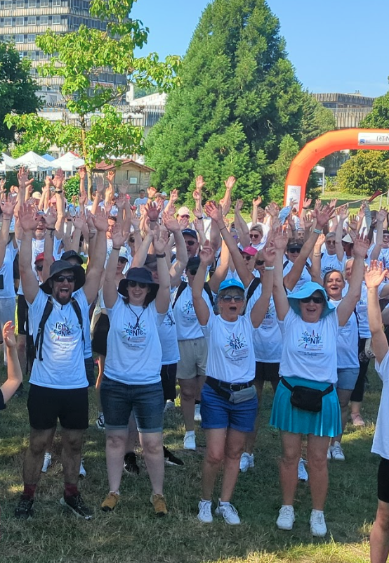 Groupe de participants en plein air levant les bras en signe d’énergie et de cohésion lors d’un événement collectif.